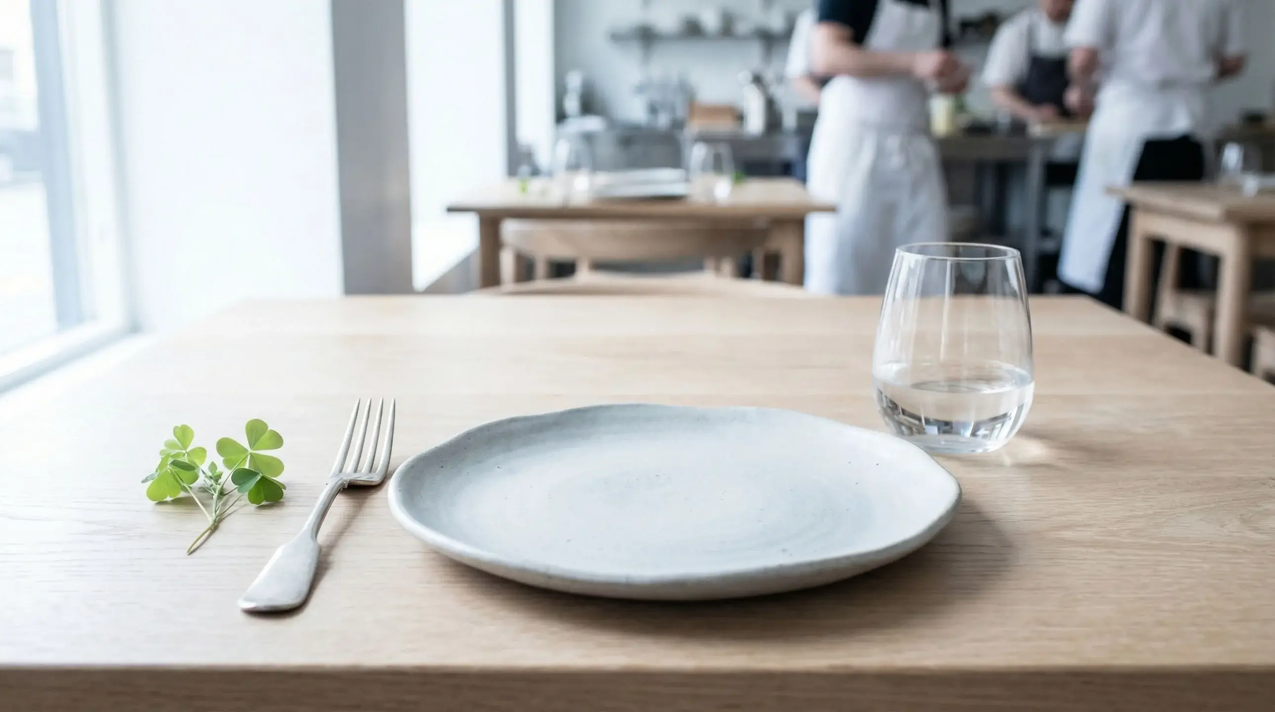 Close-up of an elegant place setting with artfully arranged foraged ingredients on a handmade ceramic plate