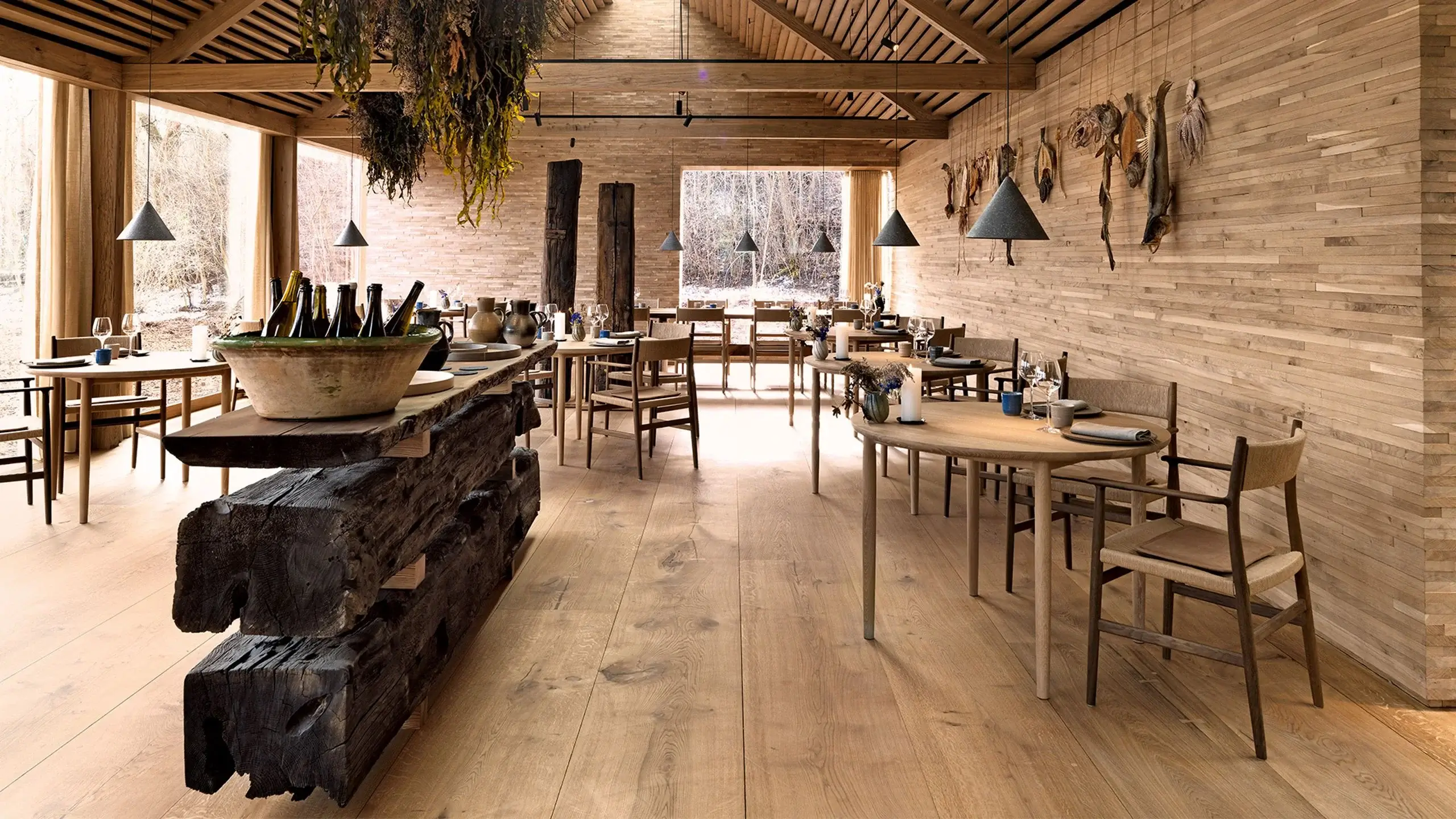 Minimalist Nordic dining table set with natural wood plates and handcrafted ceramic bowls in Fjeld's dining room